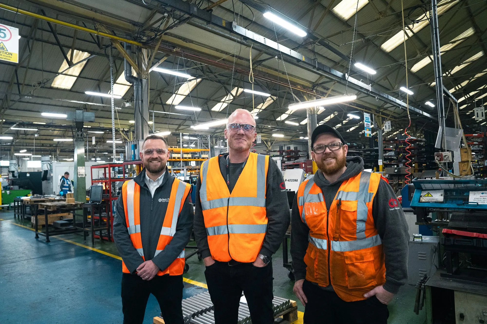Picture of thee men smiling in a factory
